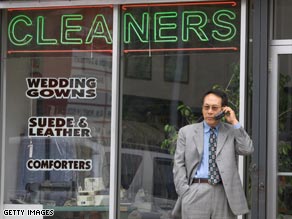 An unidentified man talks on a cell phone in front of the Chung family's shop, Custom Cleaners.