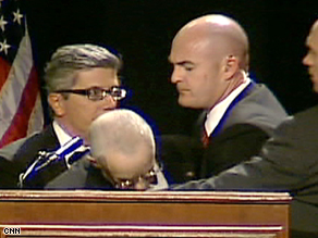 Michael Mukasey is helped as he begins to collapse during his speech Thursday night.