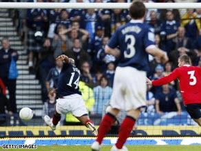 Robert Pires and Thierry Henry react after making a mistake during a penalty kick.