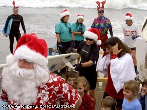 Children in Santa Cruz, California, greet Santa after he arrives on a surf board.