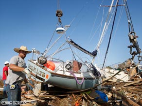 Workers on Sunday prepare to remove a sailboat washed up onto a Galveston highway by Hurricane Ike.