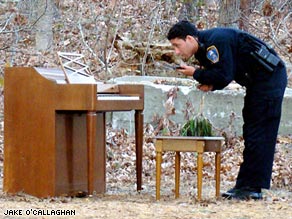 Officer Derek Dutra of the Harwich Police Department examines the mystery piano in the Massachusetts woods.