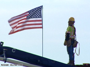 An ironworker looks at the unfurled American flag he placed atop a new building.