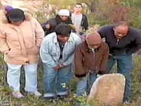 Visitors observe a gravestone at the Union Bethel A.M.E. cemetery, which could be the future site of a landfill.