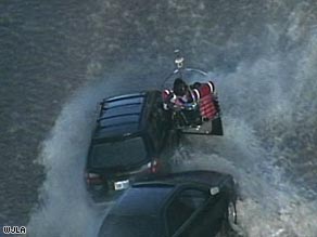 A rescuer uses a boat to reach a driver. At least 15 motorists were rescued after Tuesday's water main break.