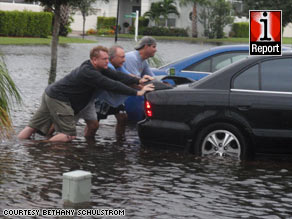 Rescue workers tend to a beached whale Tuesday on Vero Beach after Tropical Storm Fay hit.