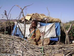 A refugee from the western Sudanese region of Darfur stands in front of a makeshift hut.
