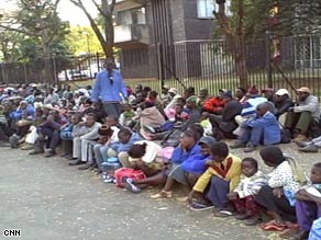 People seeking refuge sit on a curb and sidewalk outside the U.S. Embassy in Harare on Thursday.