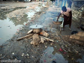 A woman prepares breakfast on a street in Gonaives, where some residents say aid is scarce. 