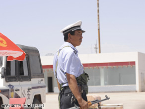 A  heavily armed policeman keeps watch at a security checkpoint in Xinjiang, China, on July 30.