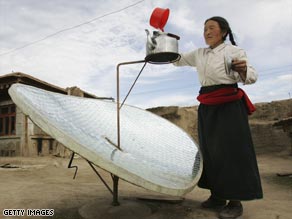 Affordable solar is reaching around the world: A Tibetan woman uses a solar water heater to boil water.