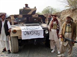 Armed militants pose next to a captured armored vehicle near the Pakistan-Afghanistan border.