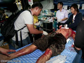A man receives medical attention after a pre-dawn blast at the Government House in Bangkok Thursday.