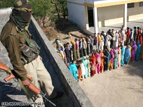 An Indian Border Security Forces soldier watches as voters in Indian-controlled Kashmir wait to vote Sunday.