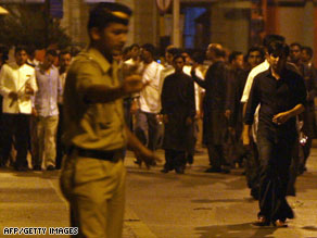 An Indian police officer directs people leaving the Taj Mahal after gunmen attacked the hotel overnight Wednesday.