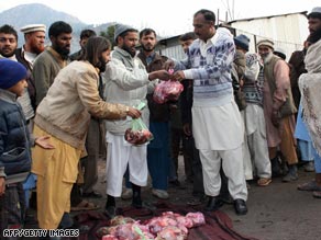 Pakistani Jamaat-ud-Dawa members, left, distribute sacrificial meat at their relief camp in Muzaffarabad.