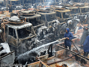 Firefighters extinguish smouldering trucks after a recent attack on a Peshawar terminal.