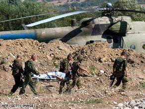 Russian soldiers carry a wounded pilot during an exchange of prisoners of war at a checkpoint in Igoeti.