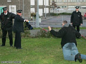 British police officers use a Taser gun to tackle a mock suspect in a training exercise.