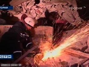 A rescue worker cuts through the rubble of the apartment building Thursday.