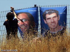 An Israeli hangs posters of the soldiers Eldad Regev, right, and Ehud "Udi" Goldwasser last month in Jerusalem.
