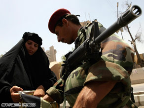 An Iraqi police commando inspects the bag of a pilgrim making her way to a Shiite shrine Monday.
