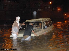 Men try to reach a vehicle carrying tourists stranded in floodwaters in the old district of Sanaa Friday.