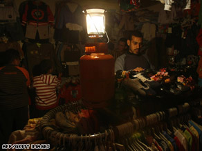 Palestinians shop by the light of a gas lamp amid electricity shortages in Gaza City on Thursday.