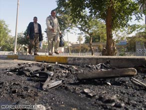Iraqis pass blown-up vehicles after a roadside bomb went off as police drove past in Baghdad on Saturday.
