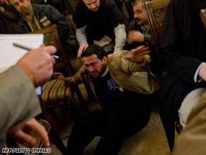 An Iraqi man is grabbed after throwing his shoes at Bush during a news briefing Sunday in Baghdad.