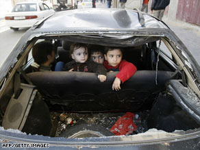 Palestinian children sit in a car with its rear window broken after an Israeli airstrike in Gaza City on Sunday.
