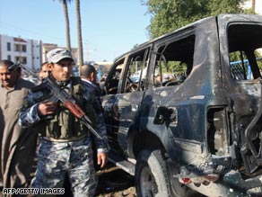 An Iraqi police officer secures the scene of a car bombing Saturday in Baghdad.