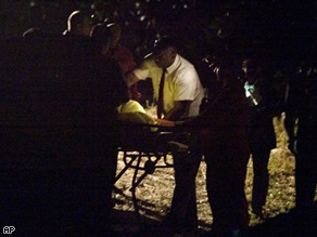 Sheriff's department personnel bundle remains onto a gurney for transport to the Coroner's office.