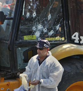 An Israeli police officer stands next to a bullet-riddled bulldozer at the scene of an attack in Jerusalem, Tuesday