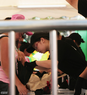 China tightens security for the Olympics. Security staff search carry-on bags of tourists in Hong Kong.