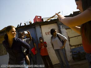 CNN's Soledad O'Brien plays with children in Diepsloot while Journey for Change participant Laura DiFilippi takes her picture.
