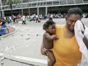 A woman cries as she waits with other flood victims at the Convention Center in New Orleans, 3 years ago
