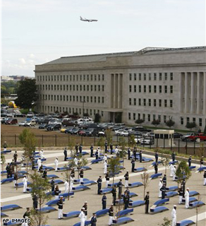 An airplane flies overhead toward Washington's Ronald Reagan National Airport as members of a Military honor guard stand at attention for the unveiling of the benches at the Pentagon Memorial, Thursday, Sept. 11,2008