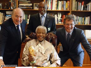 FIFA President Sepp Blatter, left, Tuesday presents Nelson Mandela with a unique replica of the FIFA World Cup to mark South Africa’s successful bid. Also present: FIFA Ambassador Tokyo Sexwale, center top, and FIFA Secretary General Jerome Valcke, right.