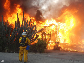 A firefighter stands by as two mobile homes go up in flames early Monday morning,  north of Los Angeles. Intense Santa Ana winds swept into Southern California Monday and whipped up a 3,700-acre wildfire, burning mobile homes and industrial buildings and forcing the evacuation of eight patients from a nearby hospital.