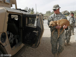 A U.S. soldier of 101st Airborne Division carries a dog before putting it in an army vehicle leaving Inshon patrol base in Youssifiyah, Iraq, as U.S troops handed over the camp to the Iraqi army Monday