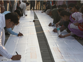 People sign messages of condolence on a banner in memory of those killed in the recent terror attacks in Mumbai.