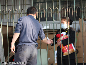 An employee at Beijing hotel that is under quarantine receives supplies from her husband Sunday.