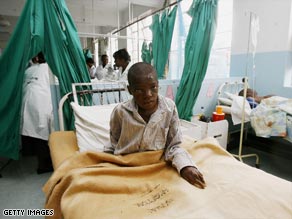 A Zimbabwean cholera patient sits in his bed  at a hospital in Harare. The rainy season could threaten more lives.