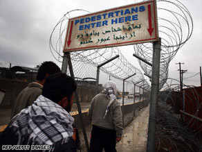 Afghan workers enter Bagram Air Field last month on a walkway protected with razor wire.