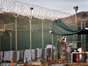 A guard leans on a fence talking to a detainee inside the U.S. Naval Base in Guantanamo Bay, Cuba.