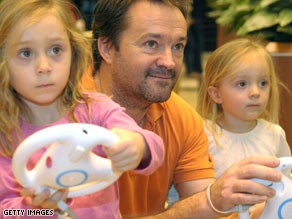 Roger Walland and daughters Rachel, 5, and Jennifer, 2, of Plano, Texas, play with Nintendo's popular Wii system.