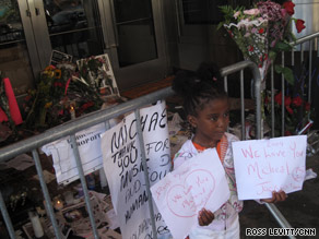 A girl holds up signs in memory of Michael Jackson outside New York's Apollo Theater on Saturday.