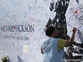 A fan signs a poster covered in messages outside the Staples Center in Los Angeles on Monday.