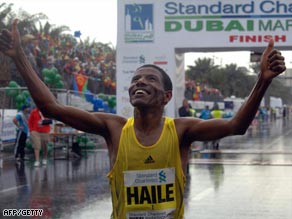 Gebrselassie crosses the finish line in damp and windy conditions in Dubai.